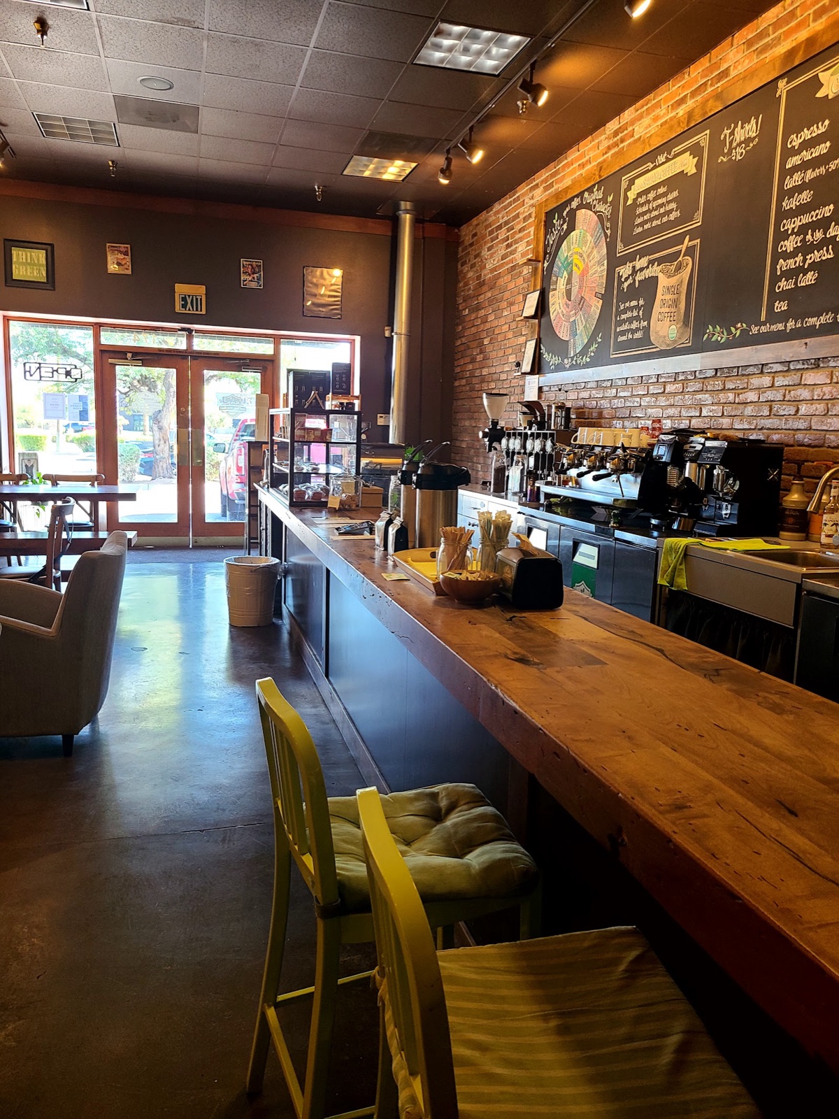 Inside Savaya: a live-edge wood coffee bar with a brick wall and chalkboard menu.