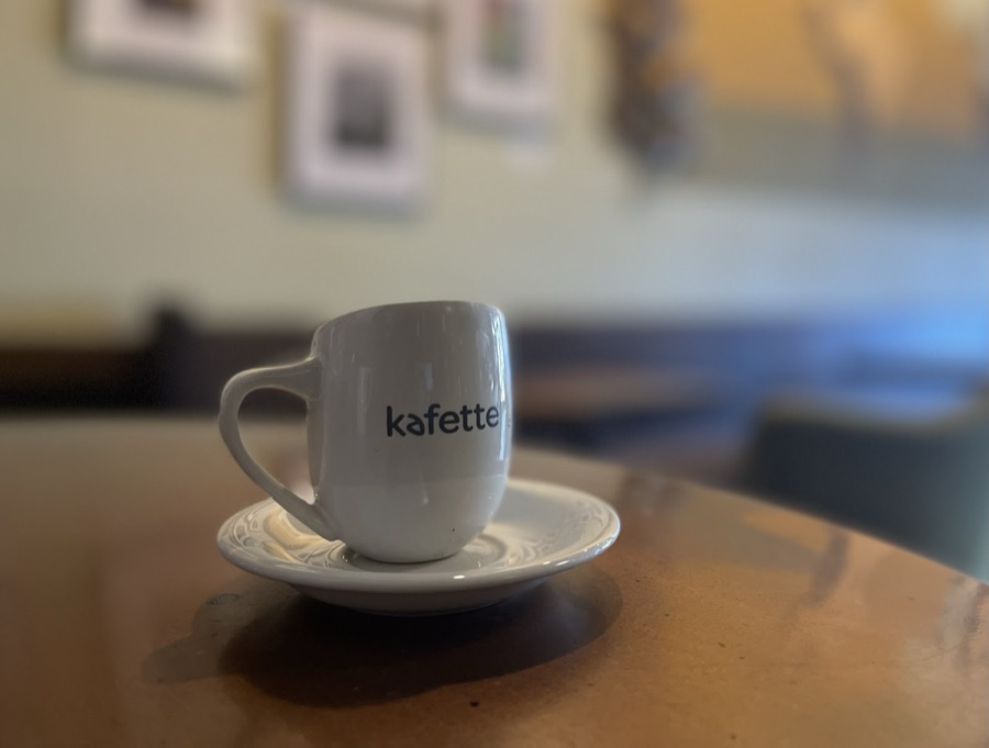 A Kafette espresso cup and saucer on a cafe table.